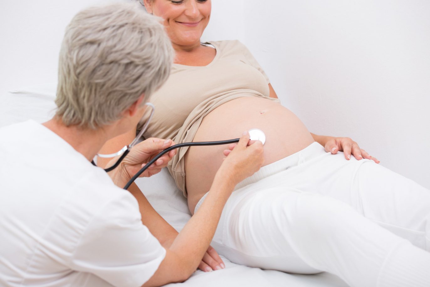 Untersuchung in der Schwangerschaft. Die Hebamme untersucht eine schwangere Frau.