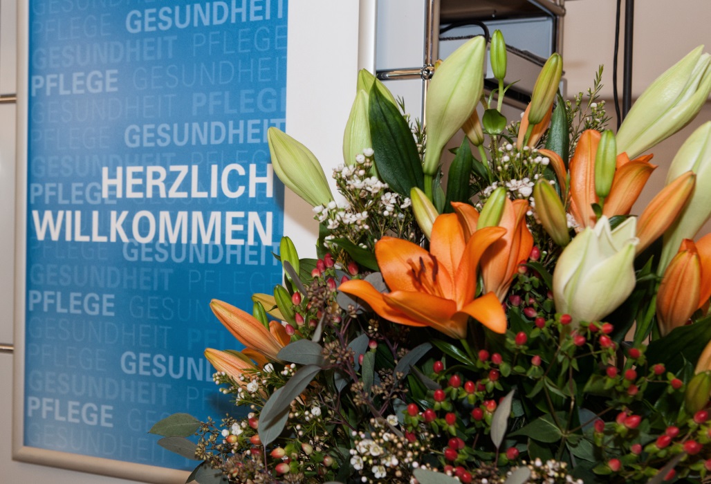 Eingangsbereich einer Veranstaltung, im Vordergrund ein Blumenstrauß.
