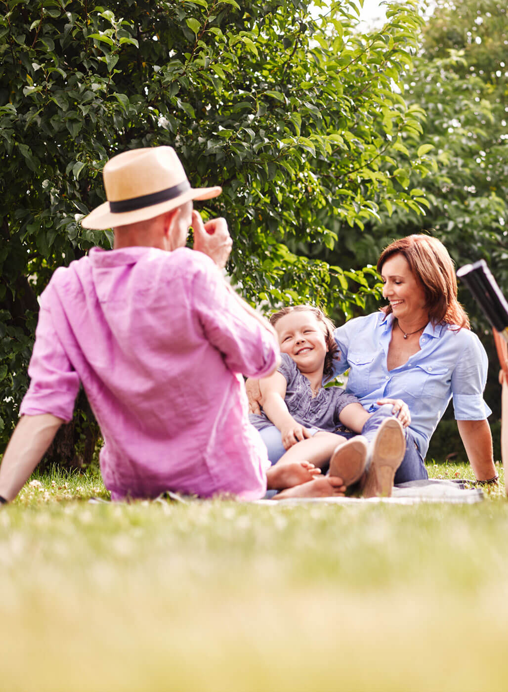 Eltern und Tochter picknicken auf einer Wiese.