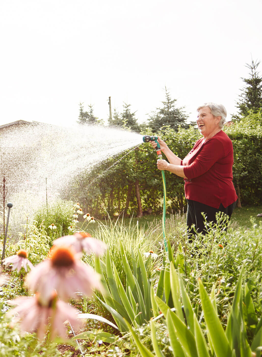 Seniorin wässert ihren Garten.