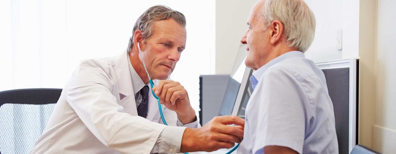 Krebsvorsorge - Arzt untersucht älteren Patienten am Oberkörper mit einem Stethoskop