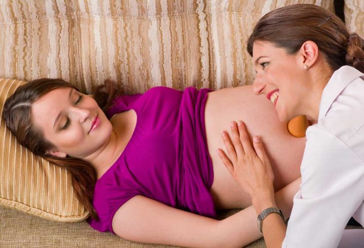 Niederlassungsprämie: Hebamme hört Herztöne am Bauch einer Schwangeren ab.