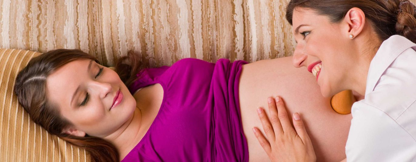 Niederlassungsprämie: Hebamme hört Herztöne am Bauch einer Schwangeren ab.