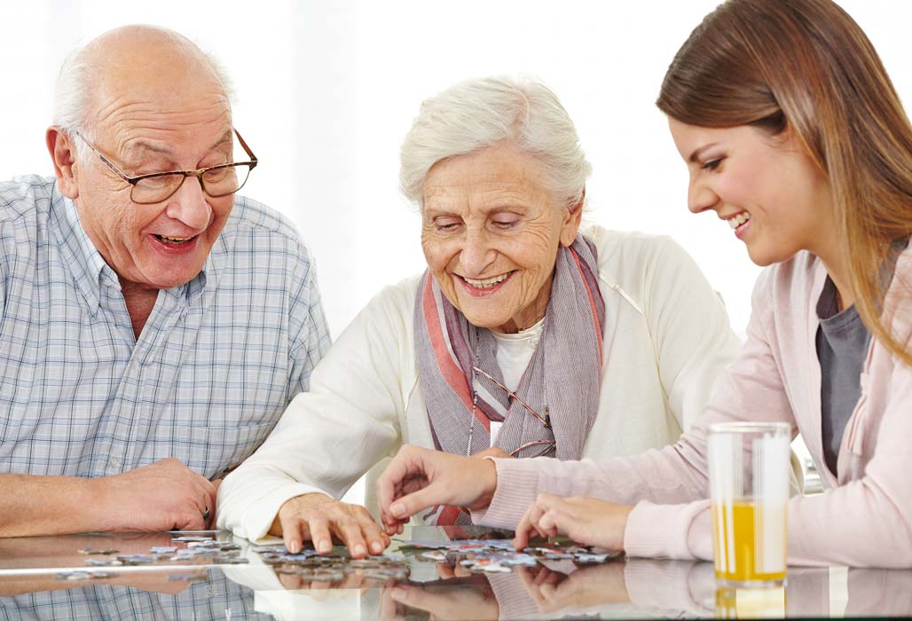 Ein älteres Ehepaar setzt mit Enkelin ein Puzzle zusammen.