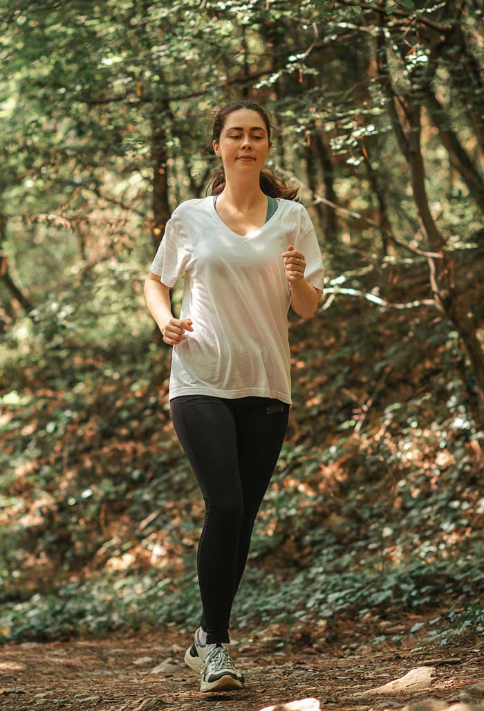 Hitze - Frau joggt mit dünner Kleidung im Wald