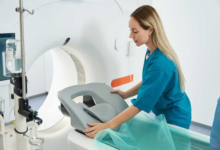 Junge medizinische Technologin für Radiologie bereitet die Liege eines Röntgengeräts vor